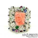 anillo con coral rosa natural grabado con rostro de mujer, rodeado de flores de diamantes esmeraldas rubíes zafiros